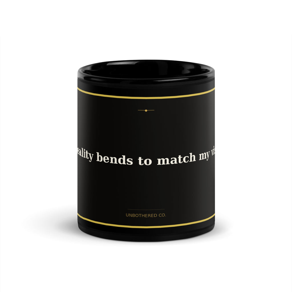 Black 11oz manifestation mug with gold text reading My Reality Bends To Match My Vision - Unbothered Co.