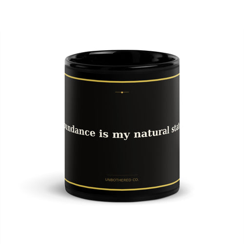 Black 11oz manifestation mug with gold text reading Abundance Is My Natural State - Unbothered Co.